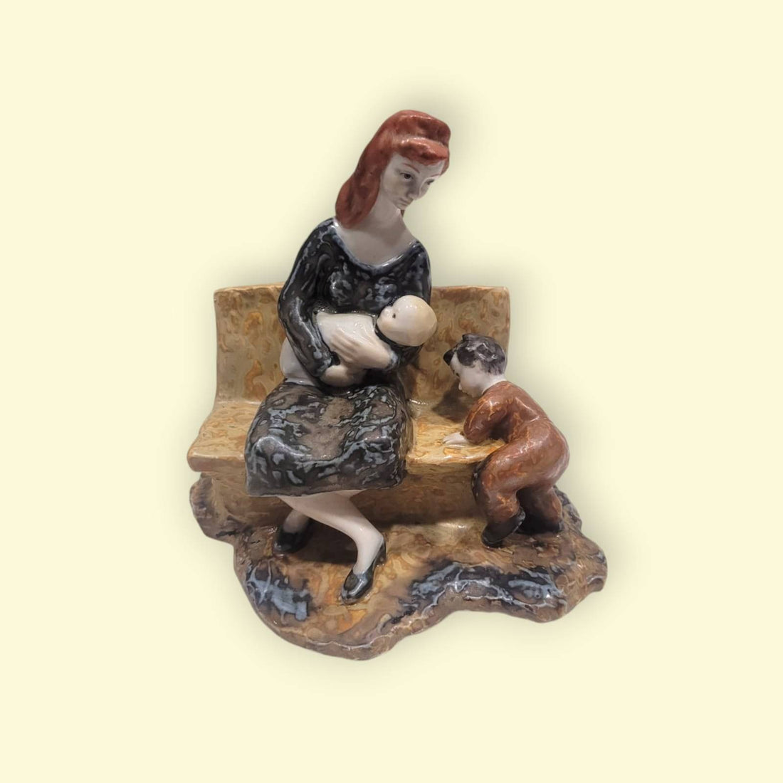 Figura de Porcelana Valenciana Nalda: madre amamantando a su bebé en un banco con niño pequeño al lado, decoración artesanal emotiva.