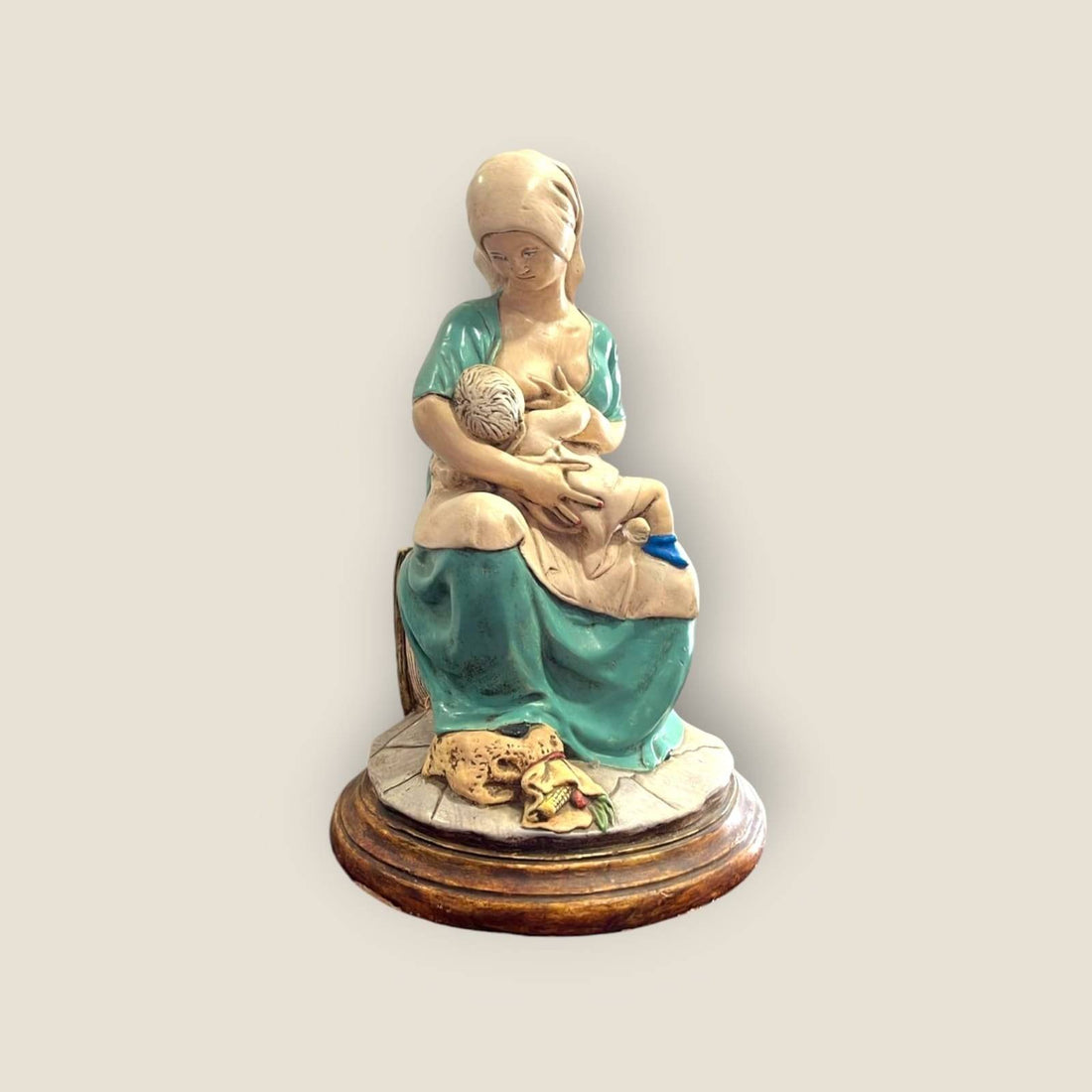 Figura maternidad amamantando en cerámica sobre base de madera, símbolo de amor natural y conexión para decoración del hogar.