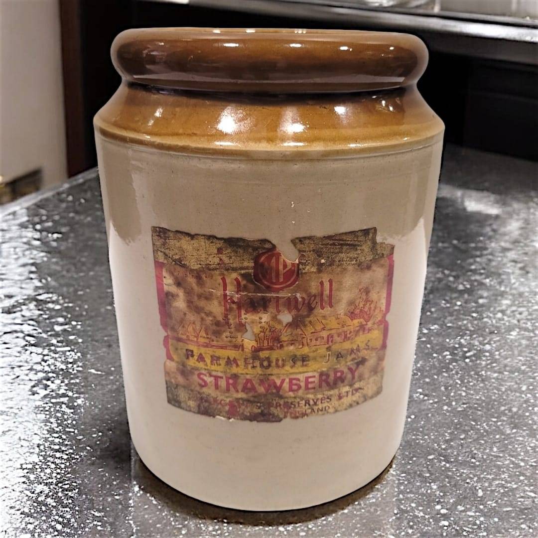 Orza de mermelada antigua de cerámica con etiqueta vintage de fresa, ideal para decoración rústica en cocinas o estanterías de estilo retro.