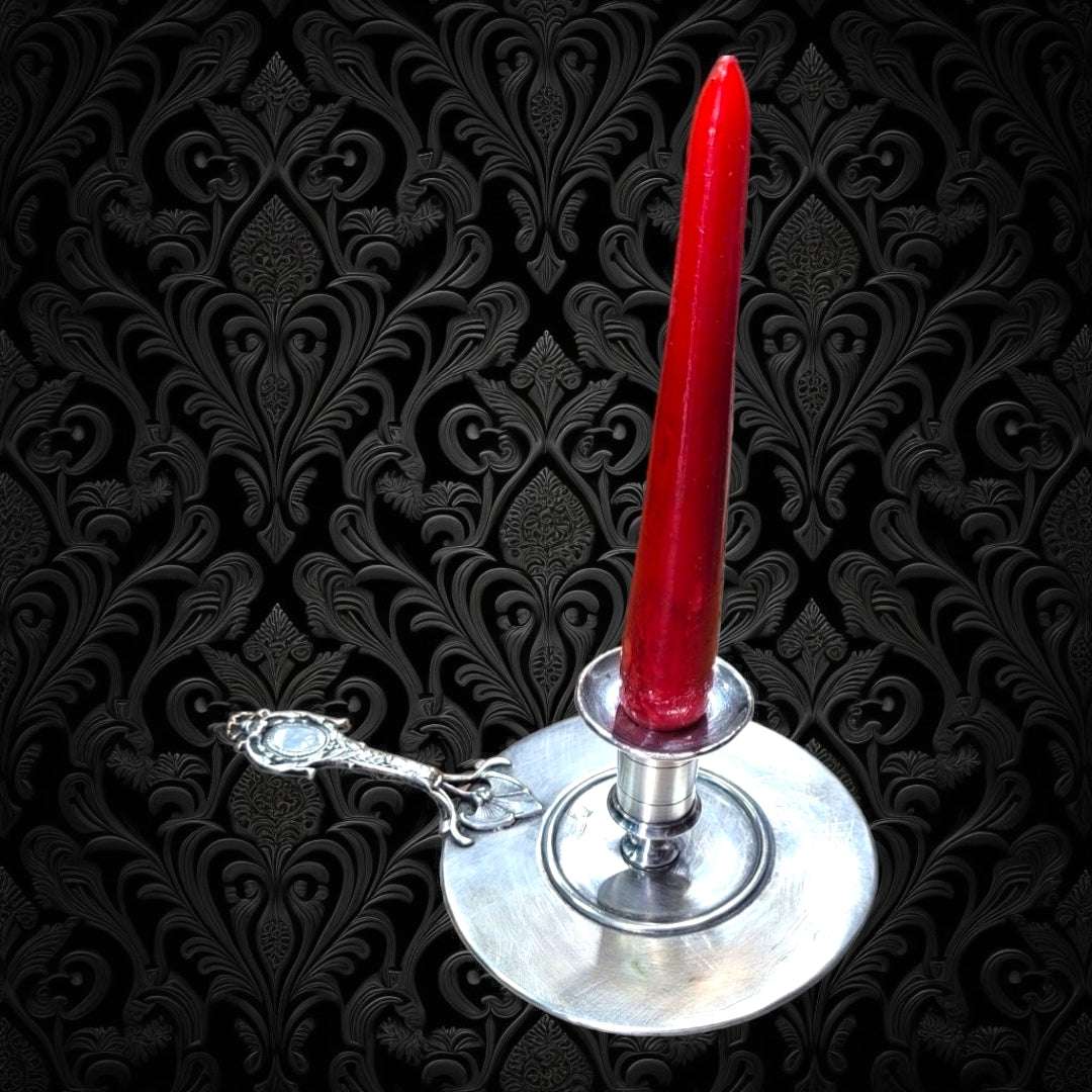 Palmatoria de Época en alpaca con vela roja sobre fondo barroco, ideal para añadir encanto vintage a tu hogar en decoración clásica.