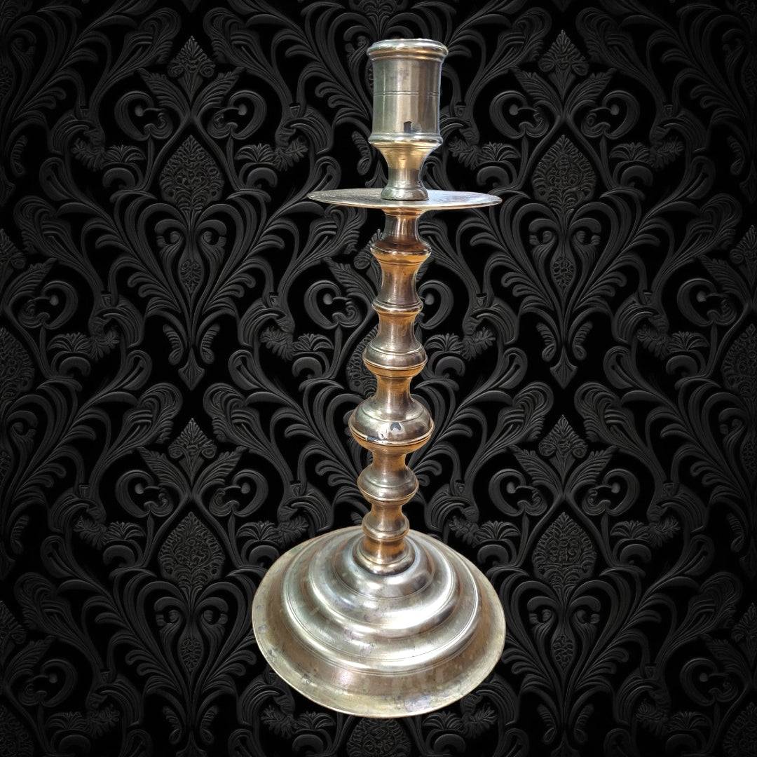 Candelero metal antiguo con diseño vintage sobre fondo decorativo negro. Candelabro elegante ideal para decoración clásica y sofisticada.