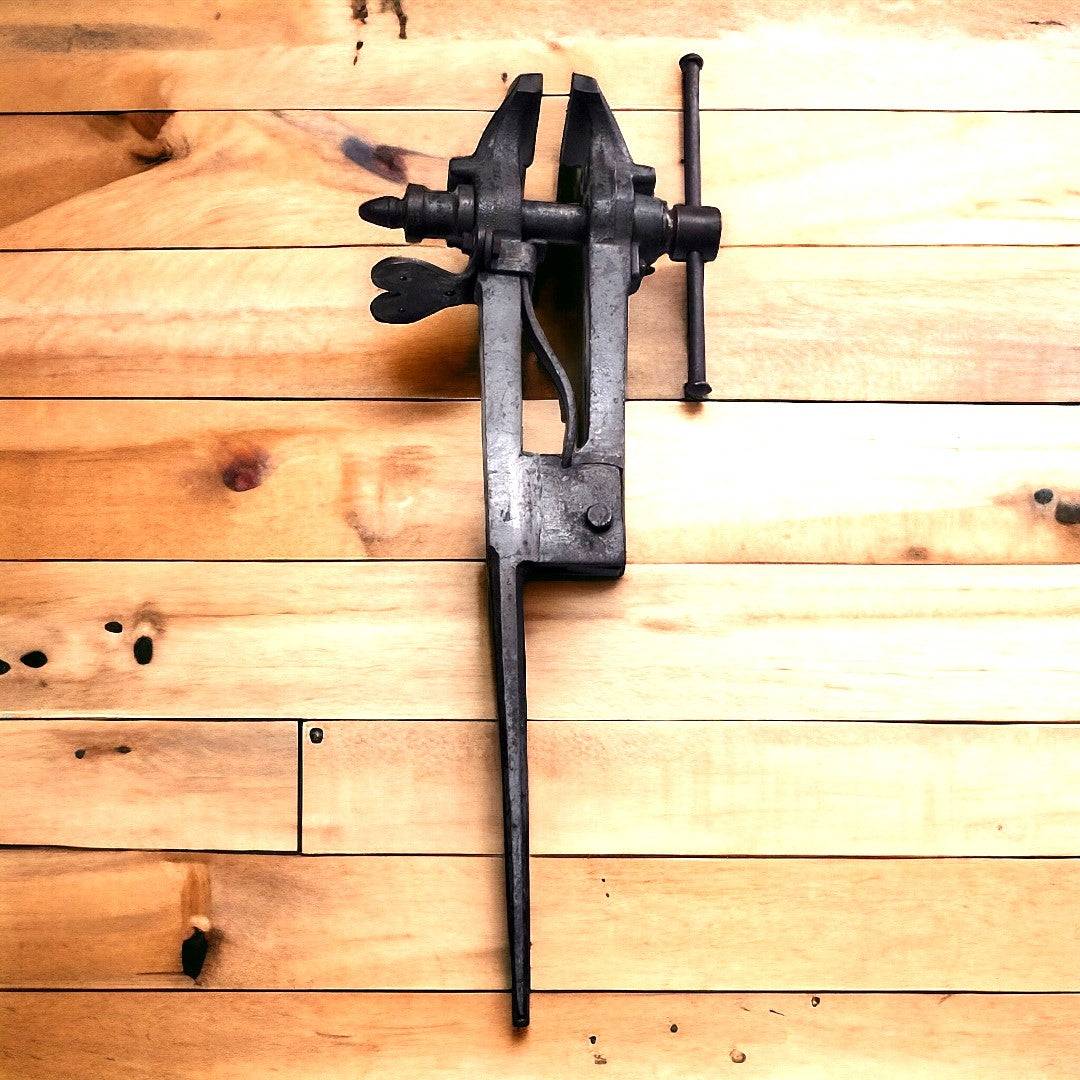 Tornillo herrero acero de fundición montado sobre madera clara, ideal como decoración rústica para taller o fragua artesanal.