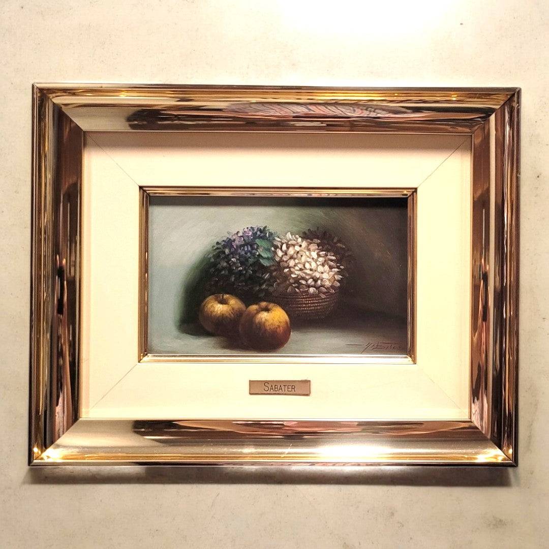 Óleo sobre tabla con membrillos y flores en cesta, enmarcado en marco metálico dorado. Firmado por Sabater, ideal para decoración de interiores.