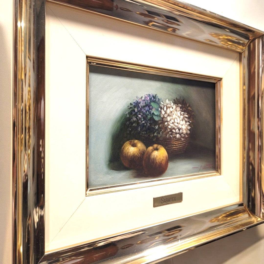 Óleo sobre tabla con membrillos y flores en cesta, enmarcado en marco metálico dorado. Firmado por Sabater, ideal para decoración de interiores.
