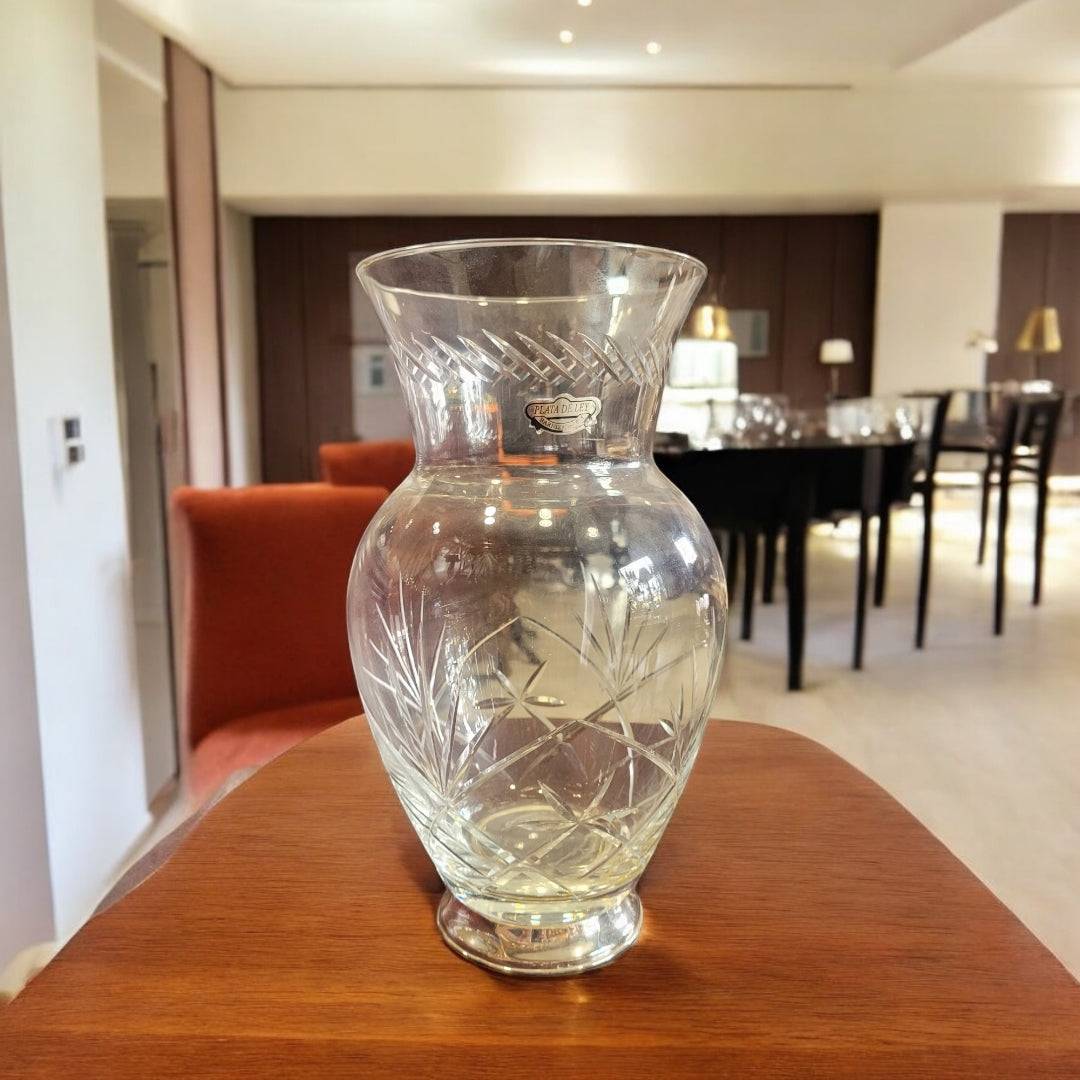 Jarrón de cristal tallado con pie de plata, estilo elegante, sobre mesa de madera en sala moderna. Ideal para decoración de interiores refinada.