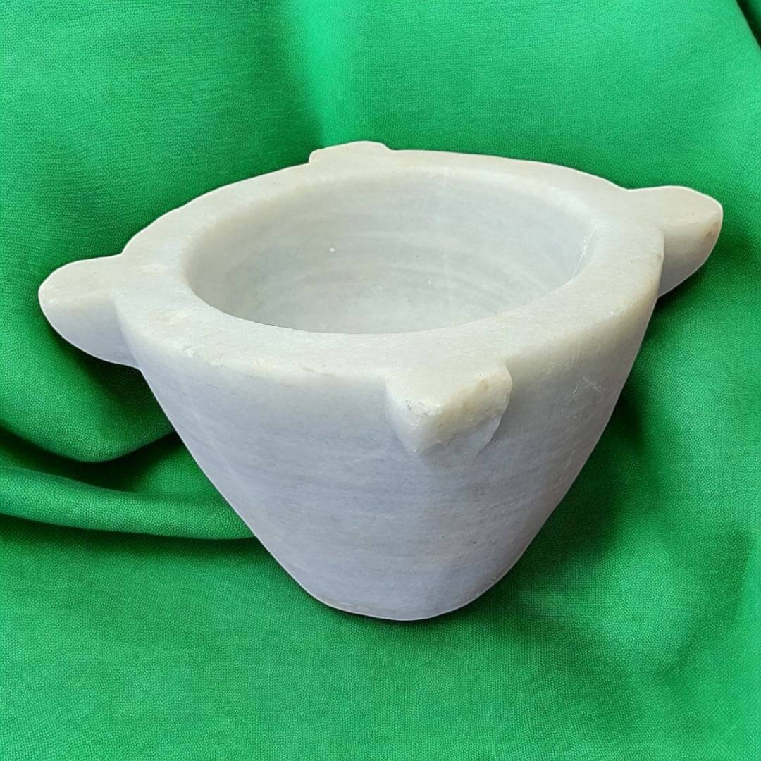 Mortero de mármol antiguo y auténtico de Cositas Antiguas, ideal para decoración de cocina o farmacia, sobre fondo verde.