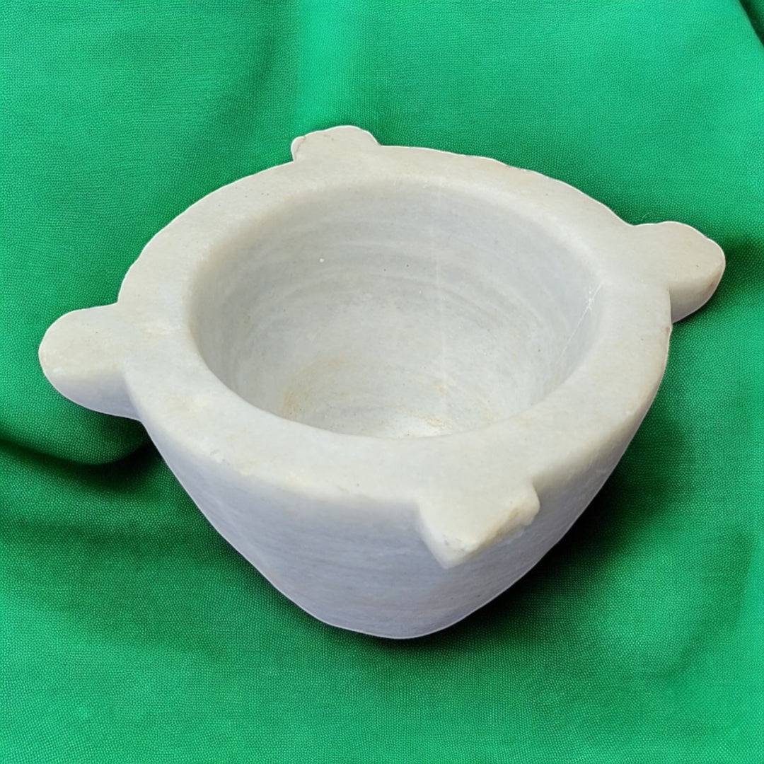 Mortero de mármol antiguo y auténtico de Cositas Antiguas, ideal para decoración de cocina o farmacia, sobre fondo verde.