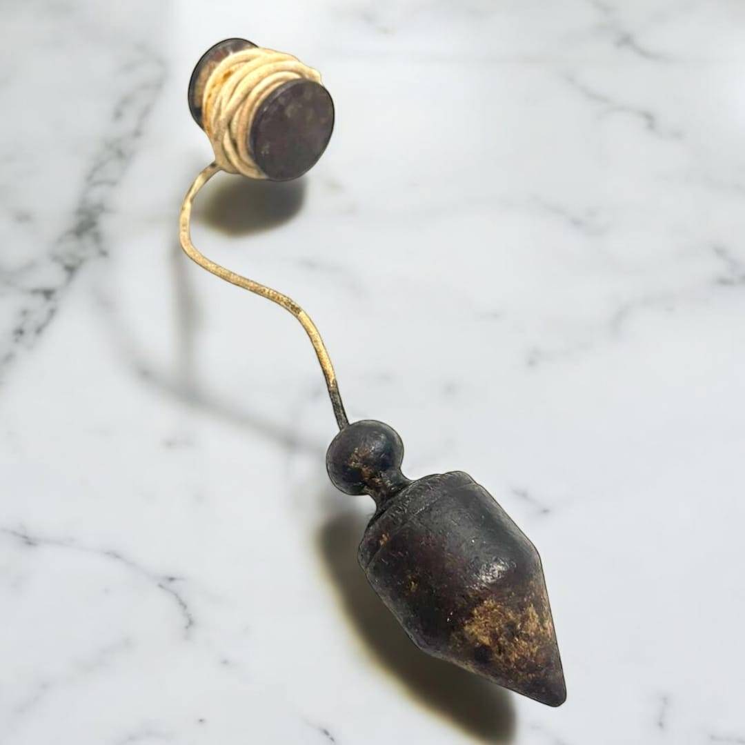 Plomada antigua: herramienta de precisión vertical histórica con cuerda enrollada, ideal para decoración vintage en hogar o jardín.