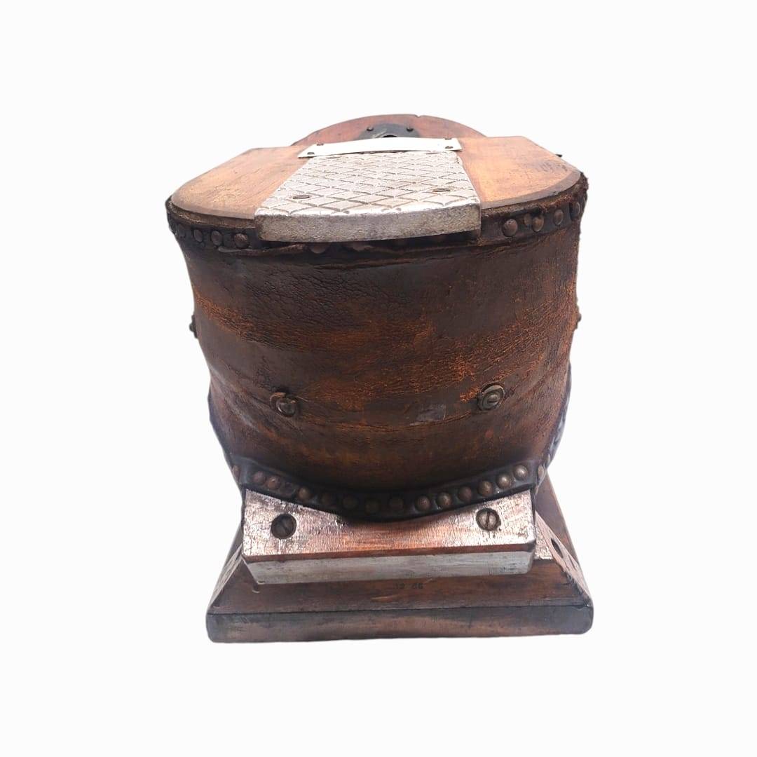 Parte trasera del fuelle de oxígeno para casco de buzo antiguo, con remaches visibles y estructura de madera envejecida.