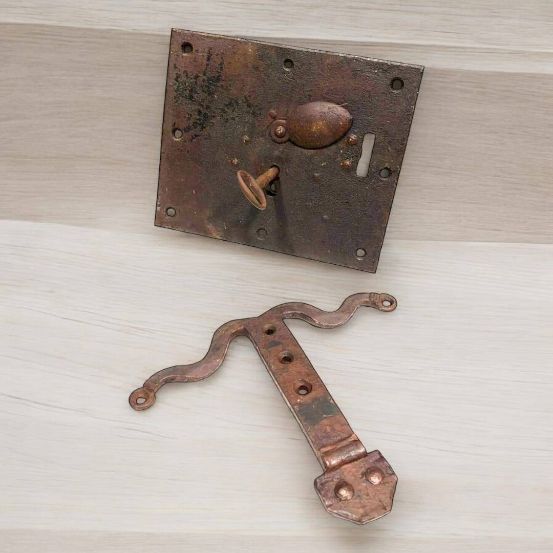 Cerradura antigua de hierro con llave montada sobre superficie clara, ideal para decoración rústica en el hogar. Diseño envejecido con estilo vintage.