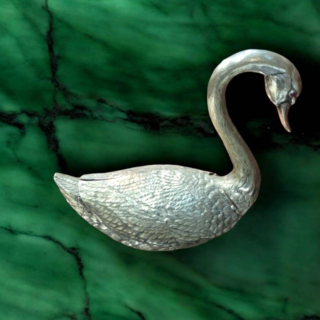 Florero cisne de metal plateado con alas abiertas, ideal para decoración elegante en el hogar. Diseño detallado que simboliza armonía y belleza.