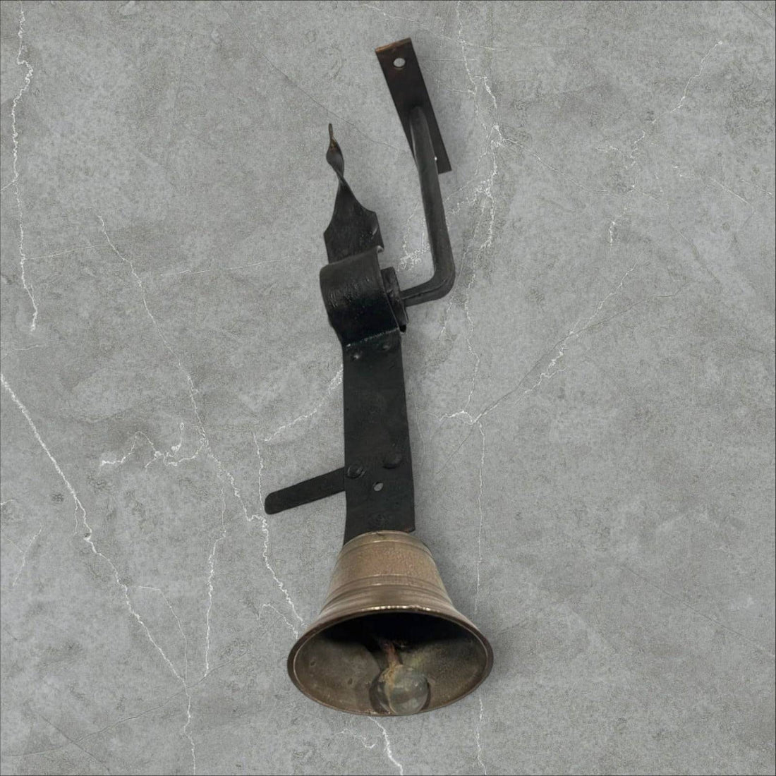 Campanilla antigua de bronce y hierro montada en pared, ideal para decoración vintage en entradas de hogar o negocio.