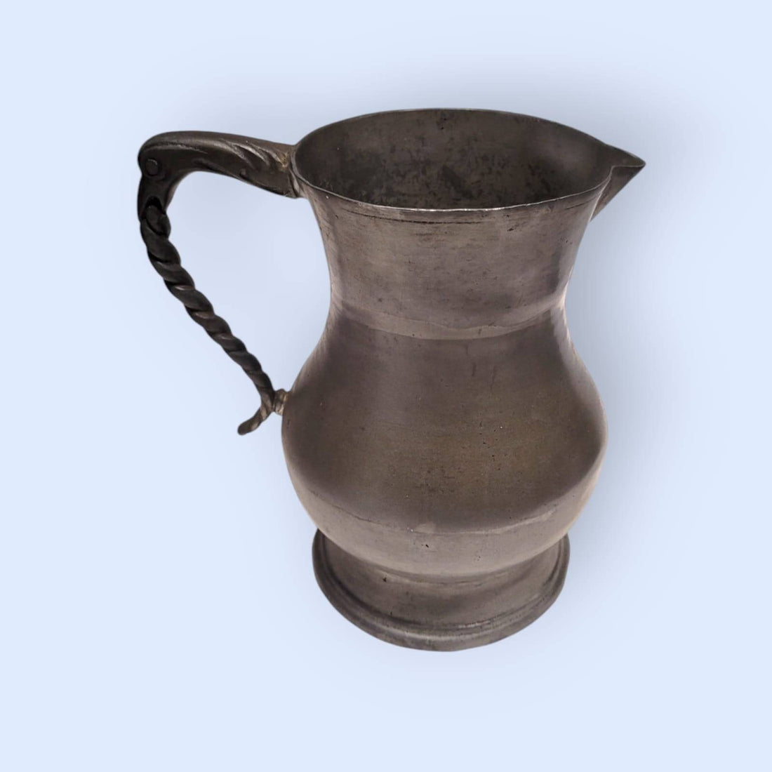 Jarra de peltre de estaño con diseño clásico y asa ornamentada, ideal para decoración vintage en hogar y jardín. Disponible en cositasantiguas.es.