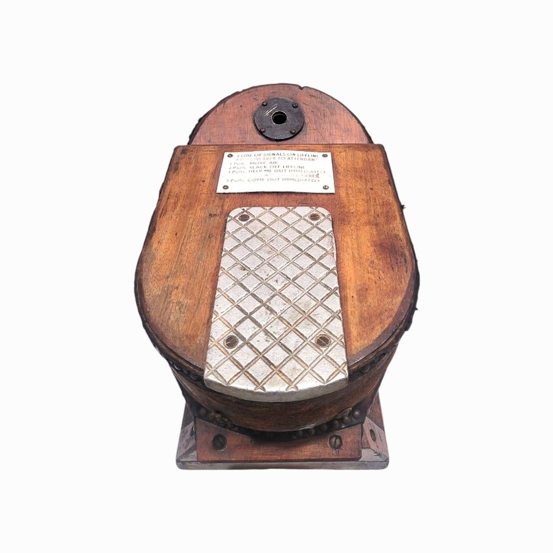 Detalle frontal del fuelle de oxígeno antiguo con placa de instrucciones y pedal metálico, pieza coleccionable de historia marítima.