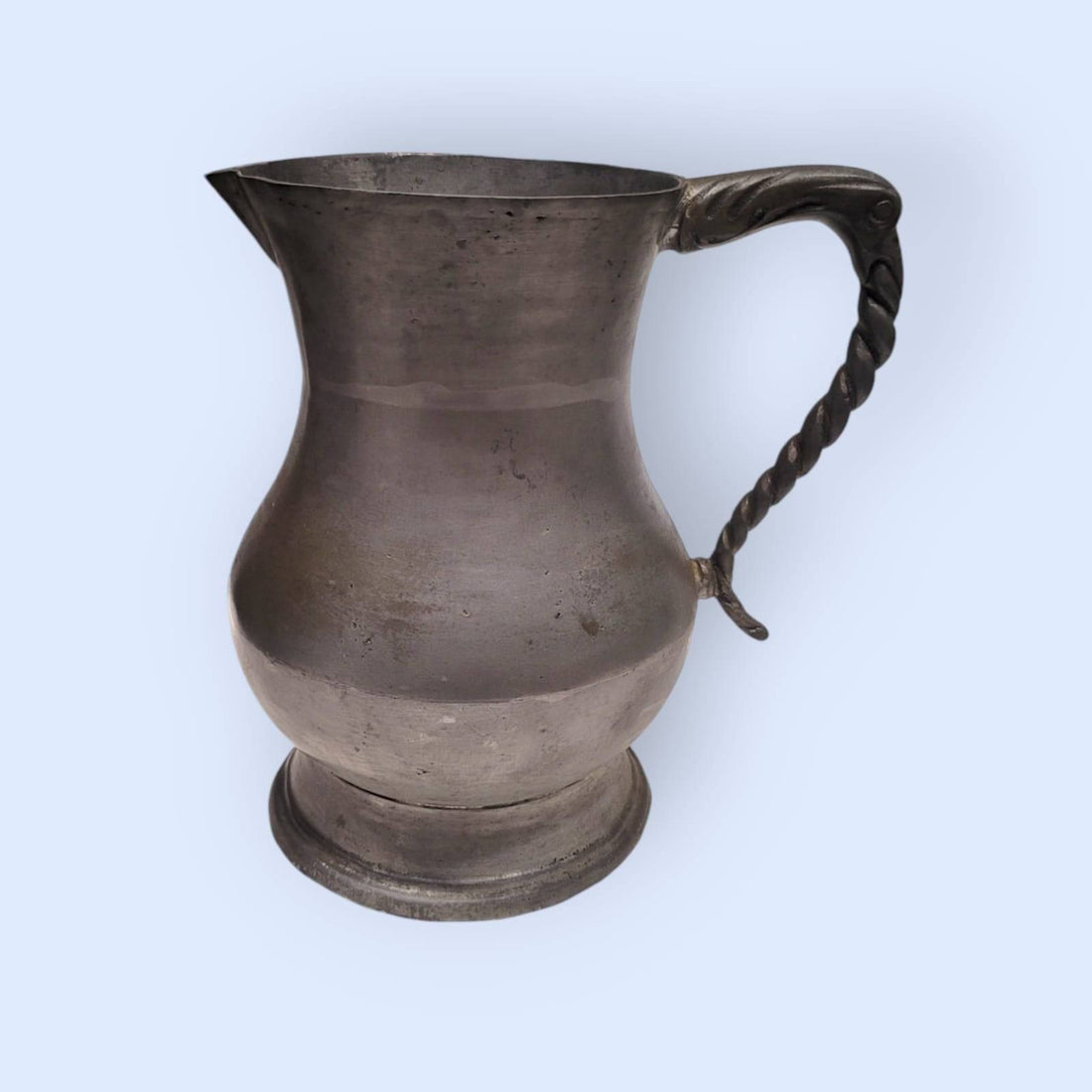 Jarra de peltre de estaño con diseño clásico y asa ornamentada, ideal para decoración vintage en hogar y jardín. Disponible en cositasantiguas.es.