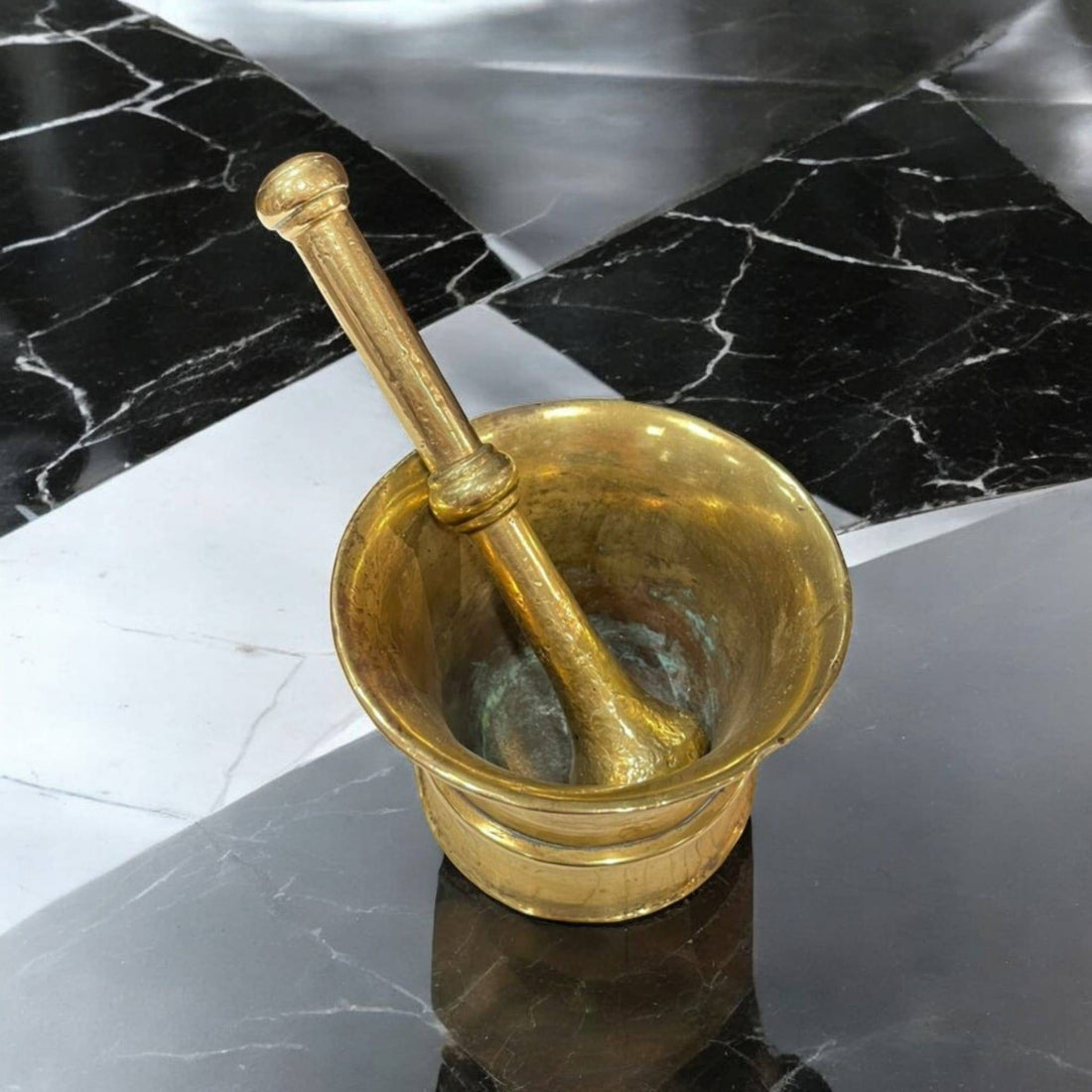 Mortero vintage en bronce con pestillo, estilo tradicional, sobre superficie negra marmoleada. Ideal para decoración clásica de cocina o comedor.