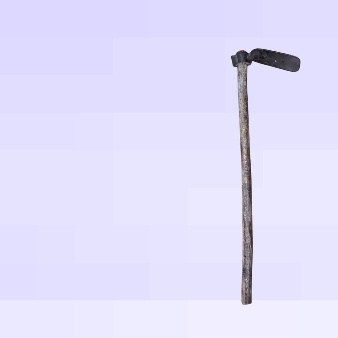 Cabeza de azada antigua de hierro forjado con mango de madera desgastado, ideal para decoración rústica en jardín o interiores vintage.