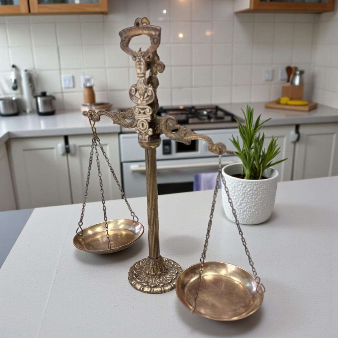 Balanza decorativa situada sobre escritorio con taza humeante y libros.