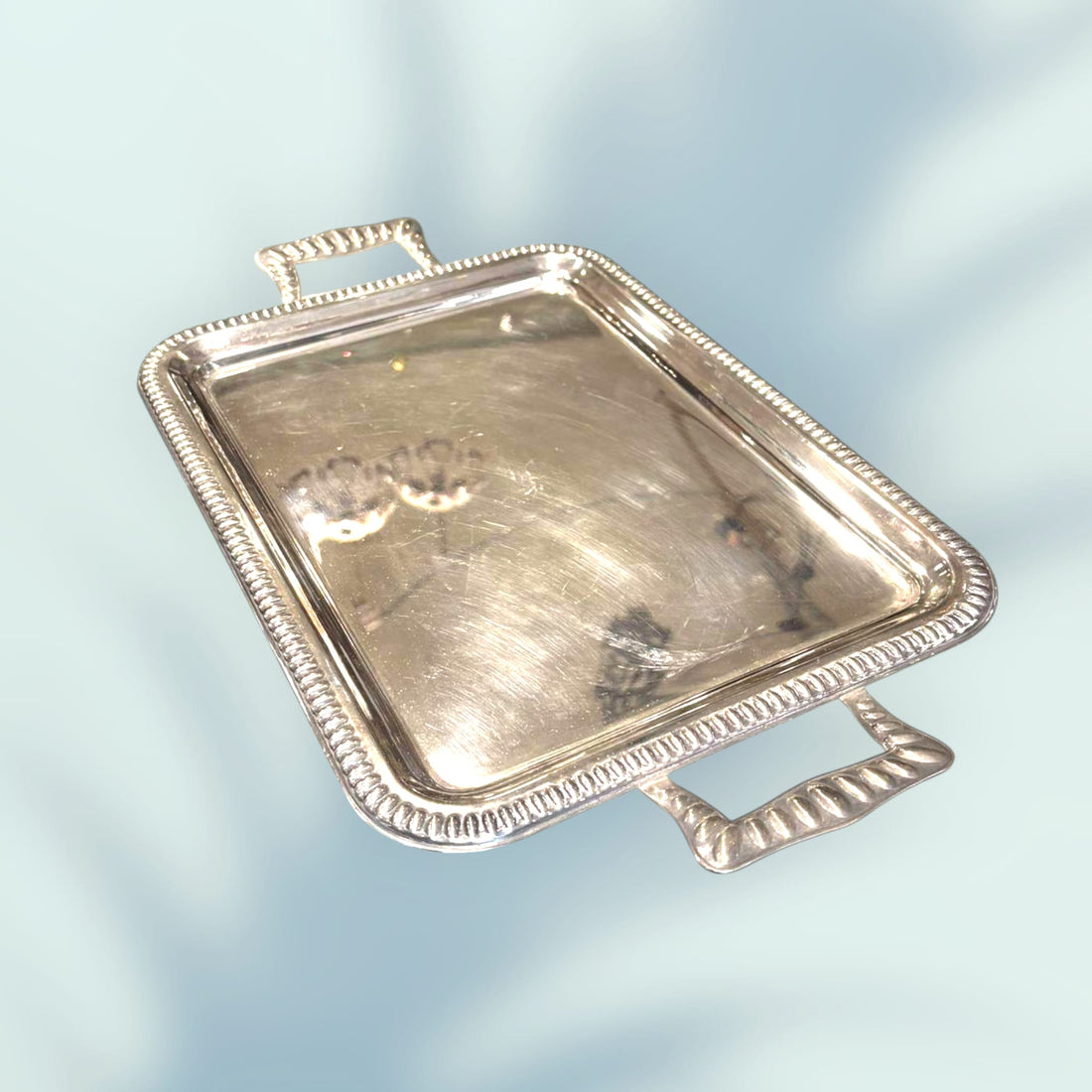 Bandeja de metal plateado con asas vista en perspectiva.