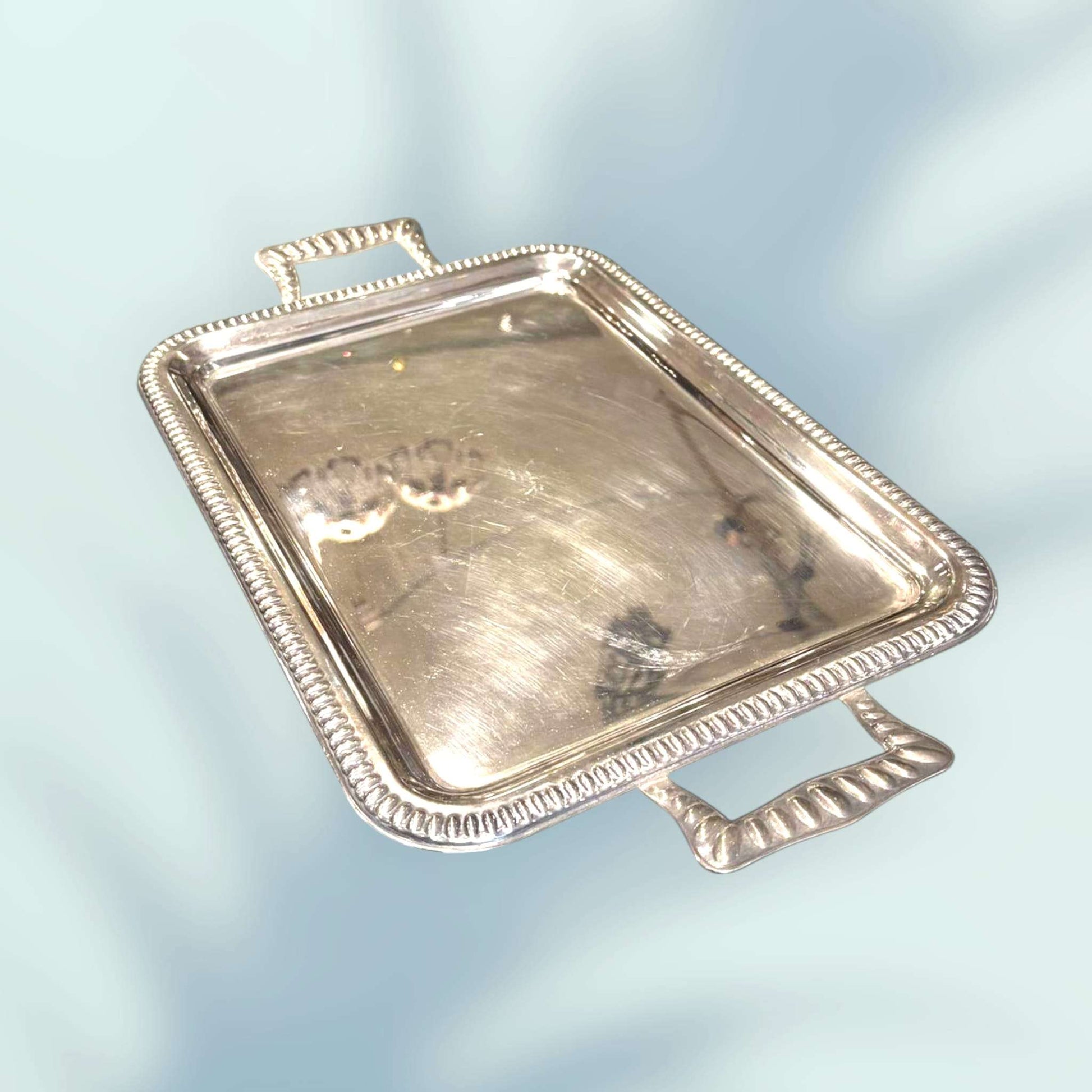 Bandeja de metal plateado con asas vista en perspectiva.
