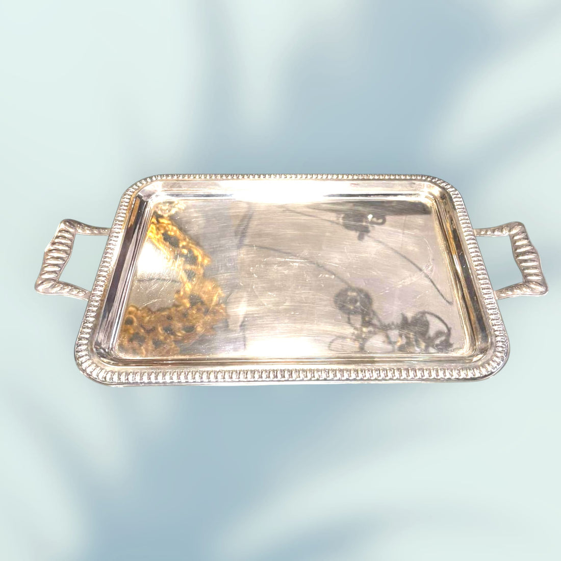 Bandeja de metal plateado con asas vista en perspectiva.