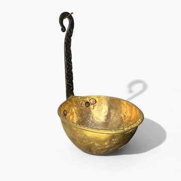 Cazo antiguo de metal dorado con mango de hierro forjado en forma curva, ideal para decoración rústica en cocina o colección vintage.