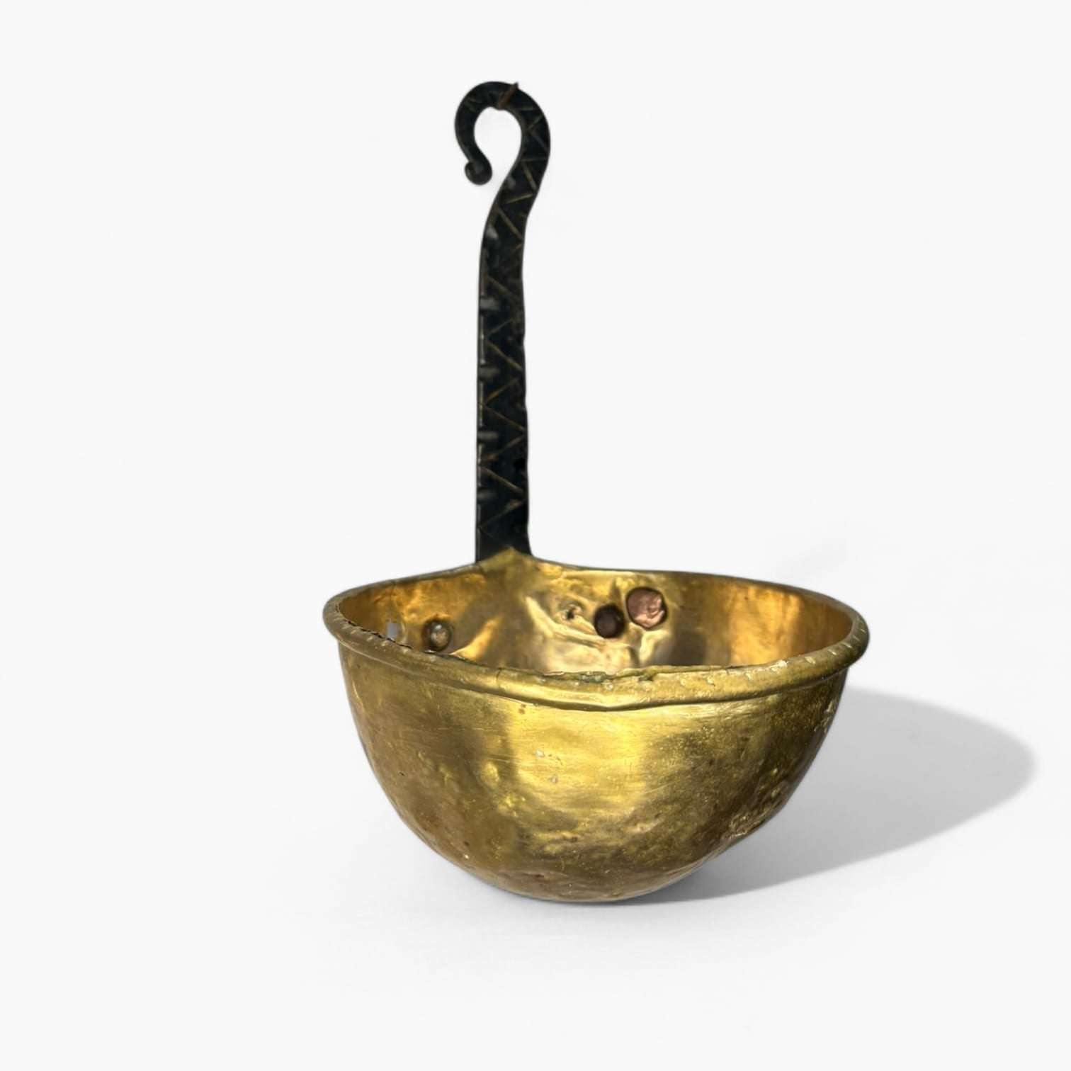 Cazo antiguo de metal dorado con acabado envejecido y mango de hierro forjado, ideal para decoración de interiores con estilo rústico.