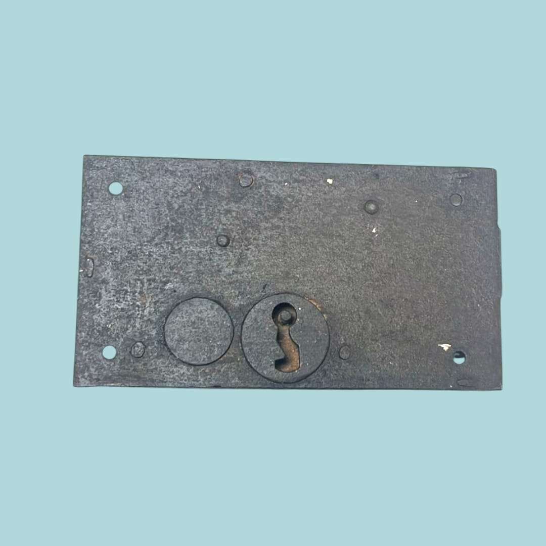 Vista frontal de la cerradura antigua de forja mostrando su diseño artesanal.