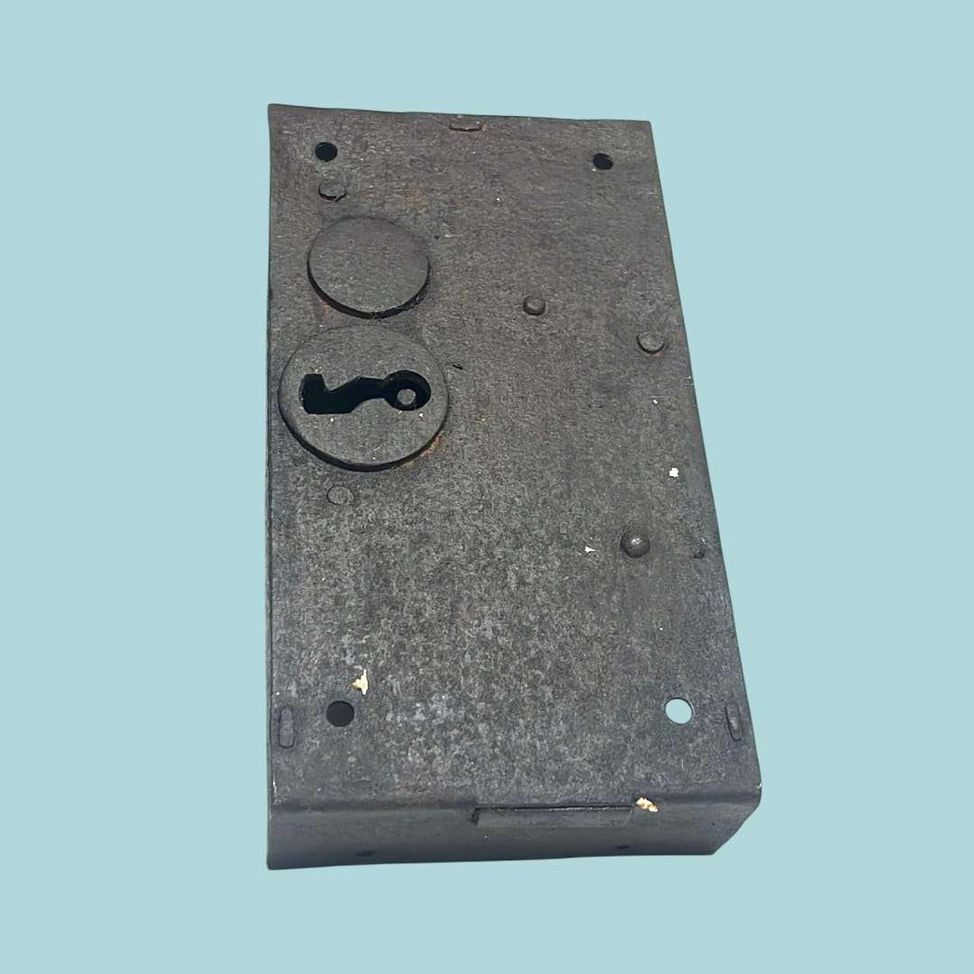 Cerradura antigua de forja vista trasera, pátina y textura del hierro.