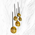 Lote de cazos antiguos con mango de forja y metal dorado colgados en pared blanca texturizada. Ideal para decoración rústica o vintage.