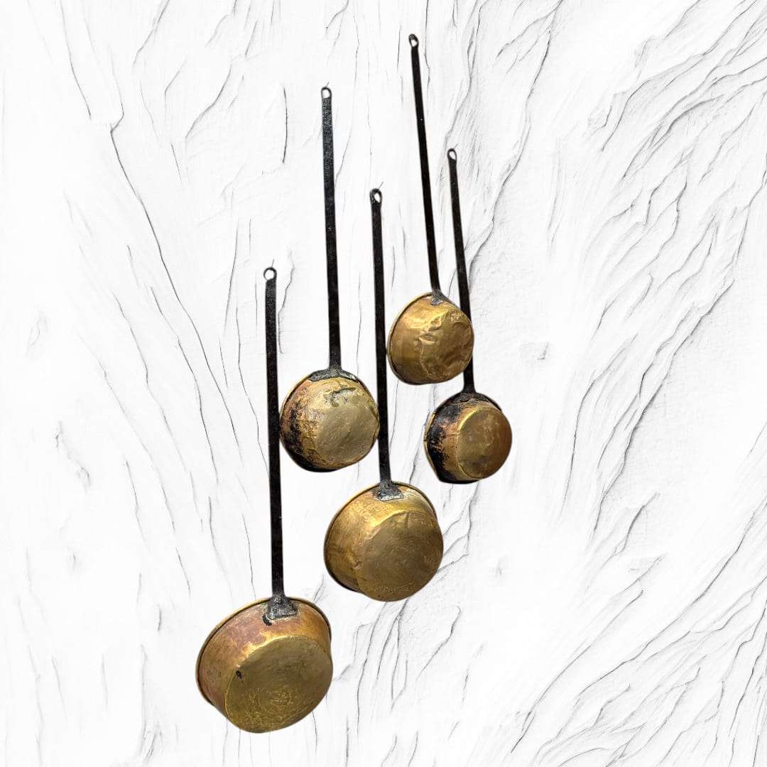 Parte trasera de cazos antiguos con mango de forja y acabado en metal dorado. Accesorio decorativo para cocina o comedor vintage.