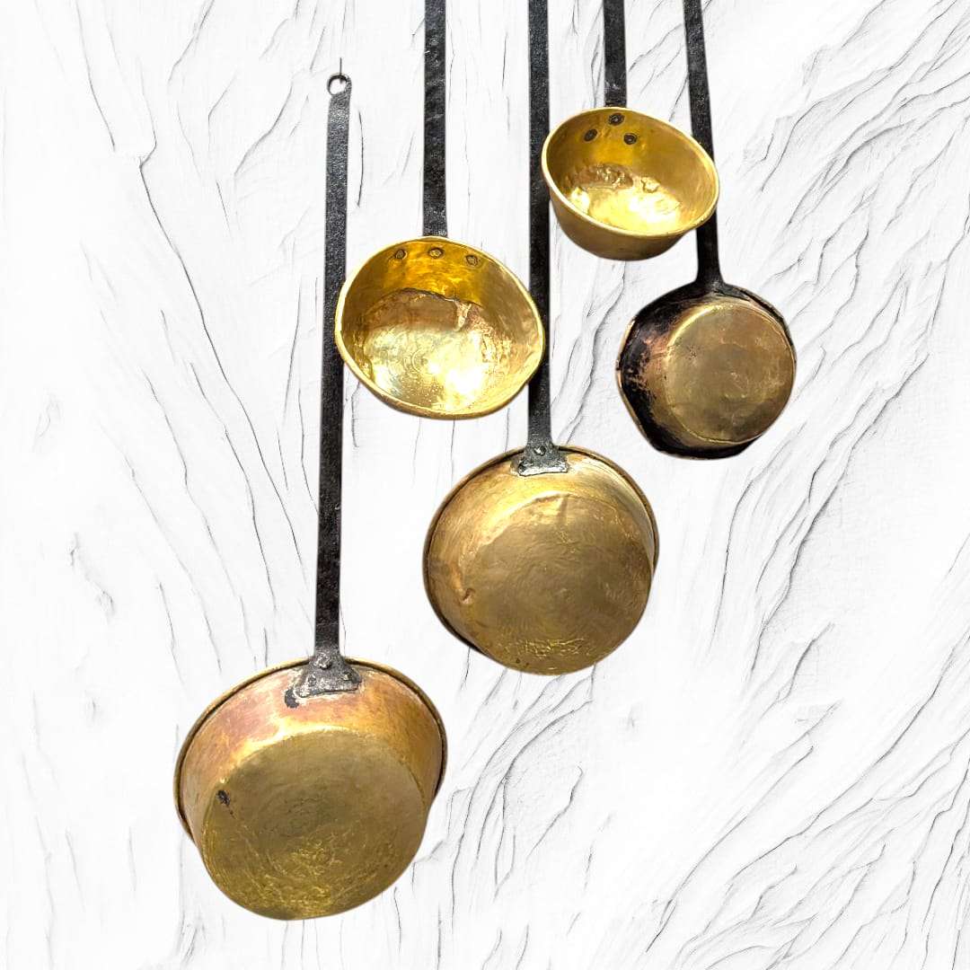 Detalle de la base de cazos antiguos con mango de forja y acabado dorado. Pieza decorativa para cocina o colección vintage.