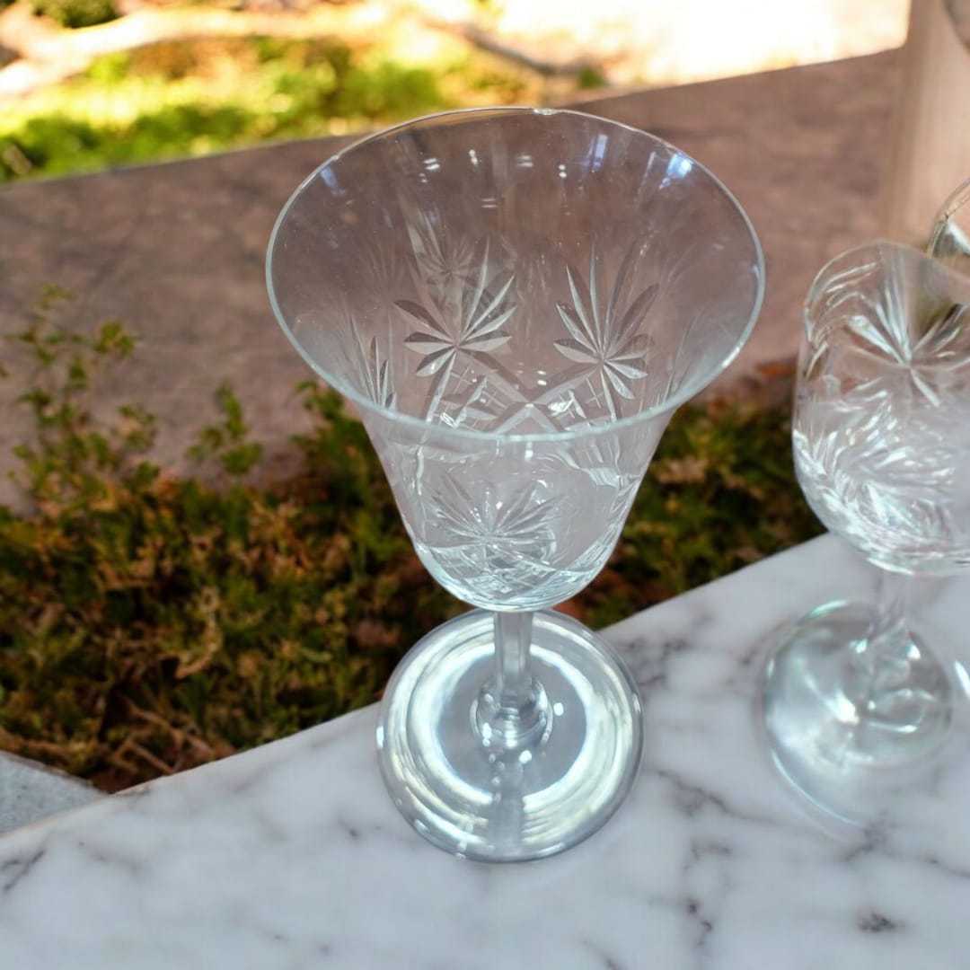 Juego de 4 copas de cristal de Bohemia tallado vintage sobre encimera de mármol, ideal para decoración elegante en el hogar o eventos especiales.