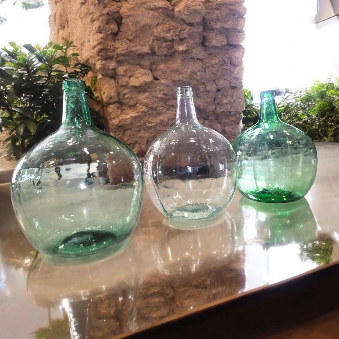 Tres damajuanas antiguas en diferentes posiciones, destacando su forma clásica y el estilo vintage que aportan a cualquier espacio.

