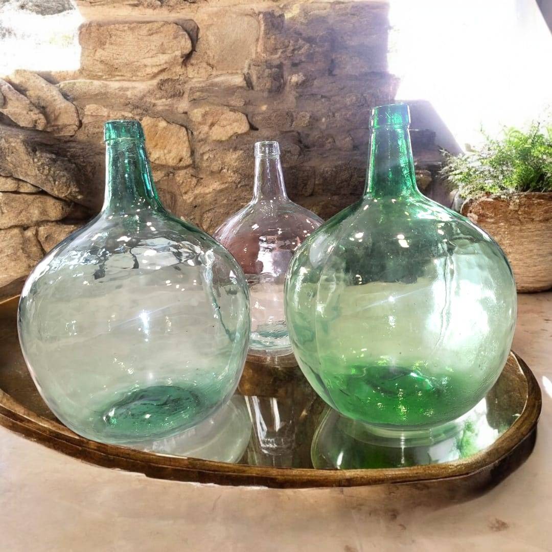 Elegantes damajuanas en una mesa rústica, resaltando su diseño artesanal y sus tonalidades naturales.