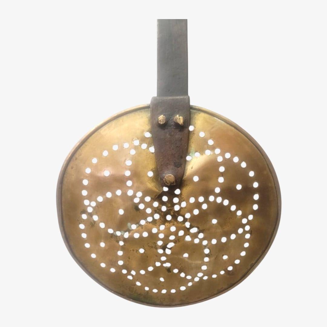 Vista trasera de espumadera antigua con mango de hierro forjado y remaches visibles. Ideal para decoración de estilo rústico o industrial.