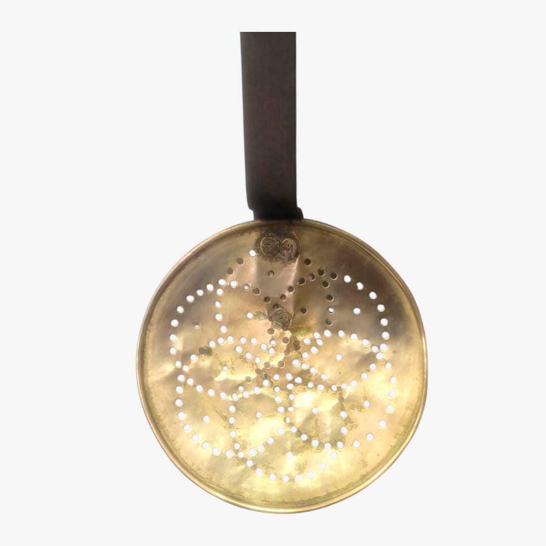 Espumadera con mango de hierro y cabezal de metal dorado, ideal para decoración vintage en cocina o pared. Diseño rústico y funcional.