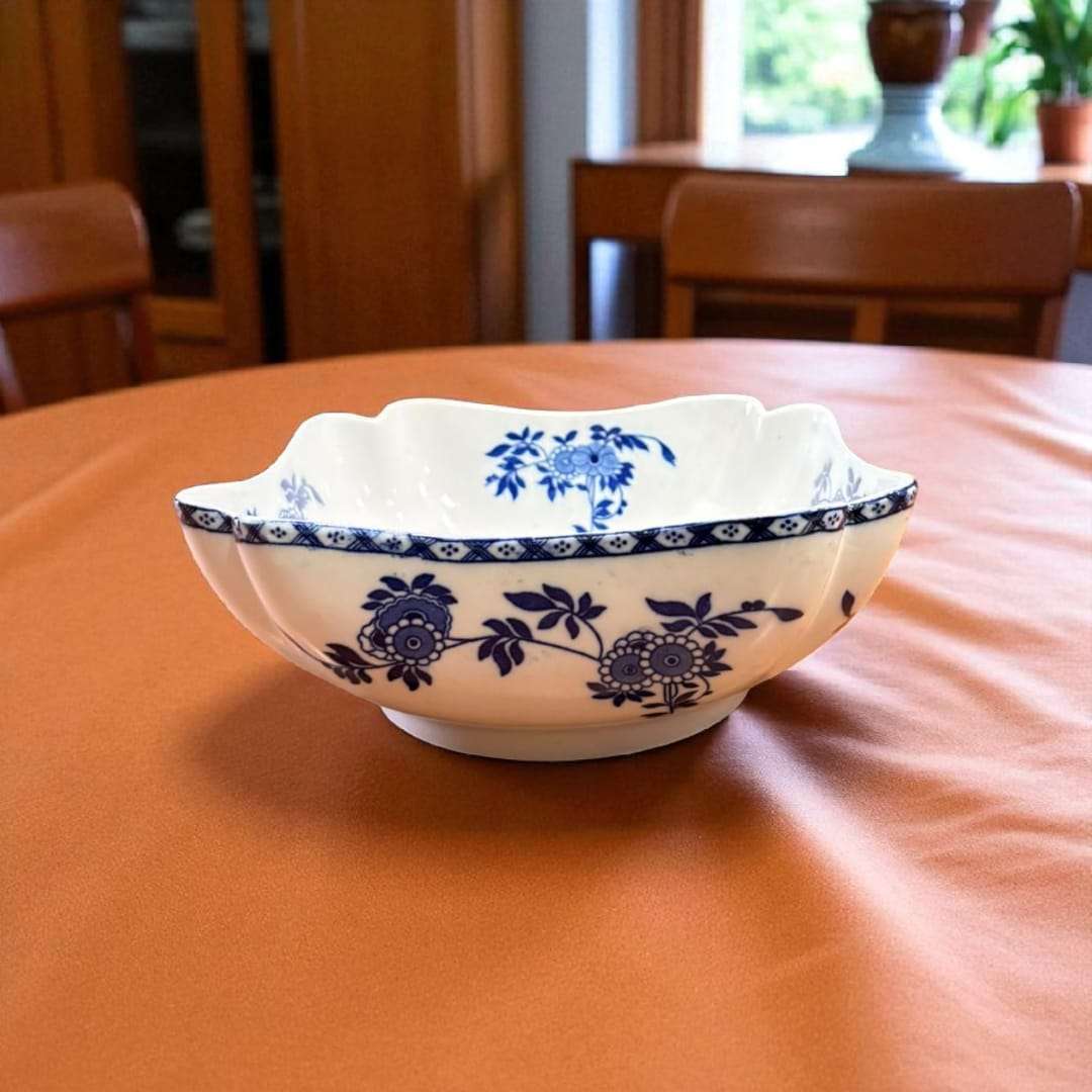 Frutero de porcelana India con decoración azul floral sobre mesa de madera.