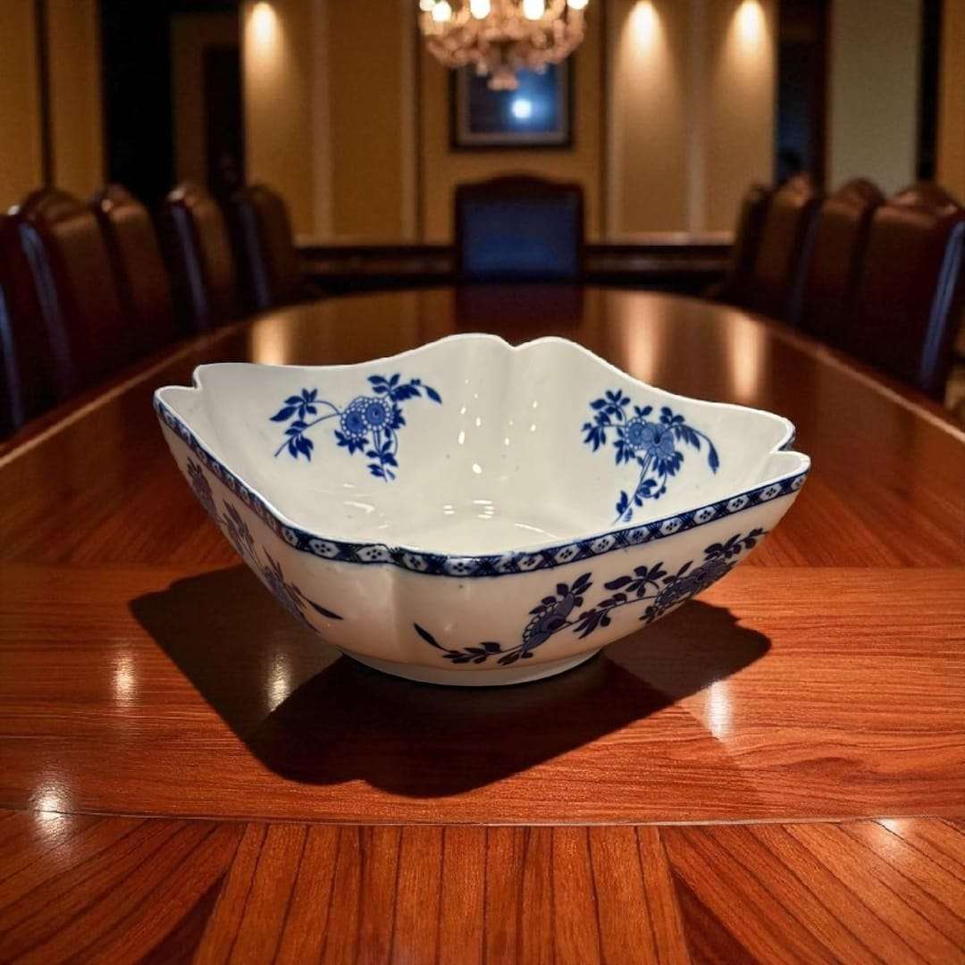 Frutero de porcelana sobre mesa de reuniones con luz cálida.