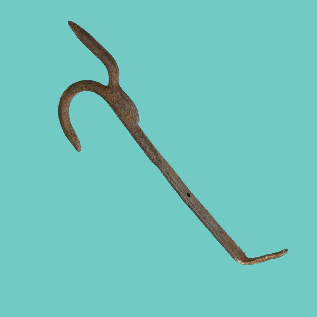 Vista completa del gancho antiguo de hierro forjado sobre fondo azul.