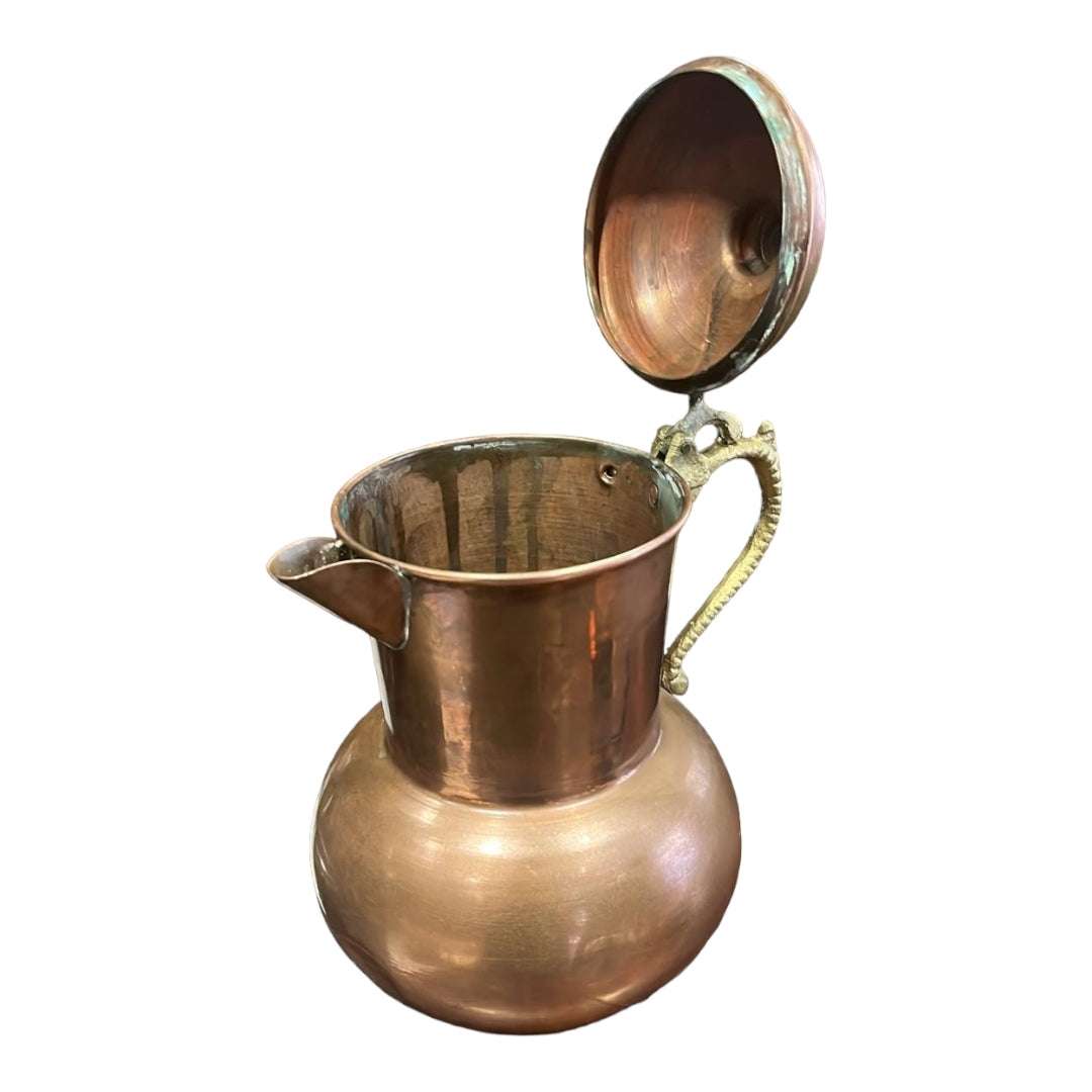Jarra de cocina en cobre con tapa abierta y asa decorativa, perfecta para añadir un toque elegante y funcional a la decoración del hogar.