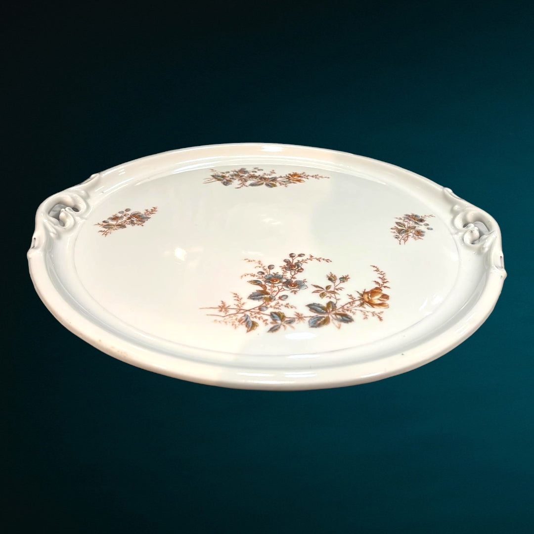 Bandeja inglesa antigua de metal grabado, capturando la luz y destacando sus detalles ornamentales.
