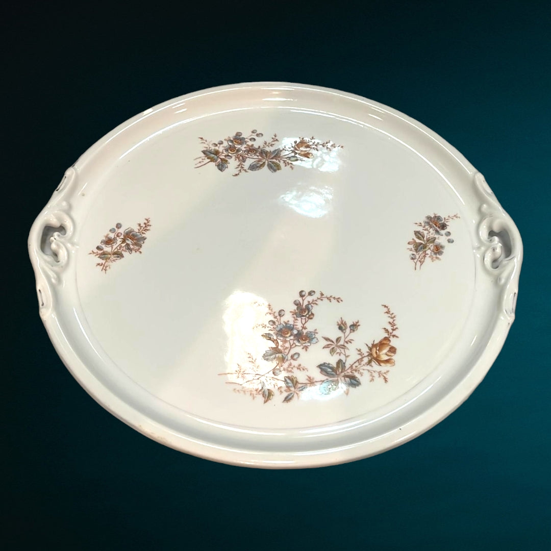 Bandeja inglesa antigua de metal grabado, capturando la luz y destacando sus detalles ornamentales.
