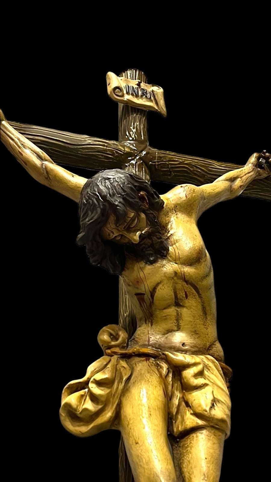 Crucifijo de terracota con Cristo en cruz arbórea frente a vitral. Decoración religiosa para el hogar que transmite paz y devoción.