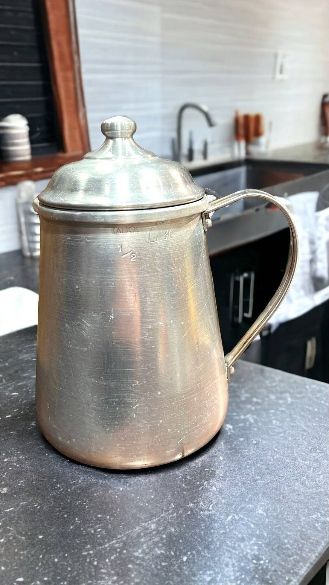 Jarra de aluminio vintage de 1/2 litro con tapadera para cocina sobre encimera moderna. Ideal para decoración retro en cocinas contemporáneas.