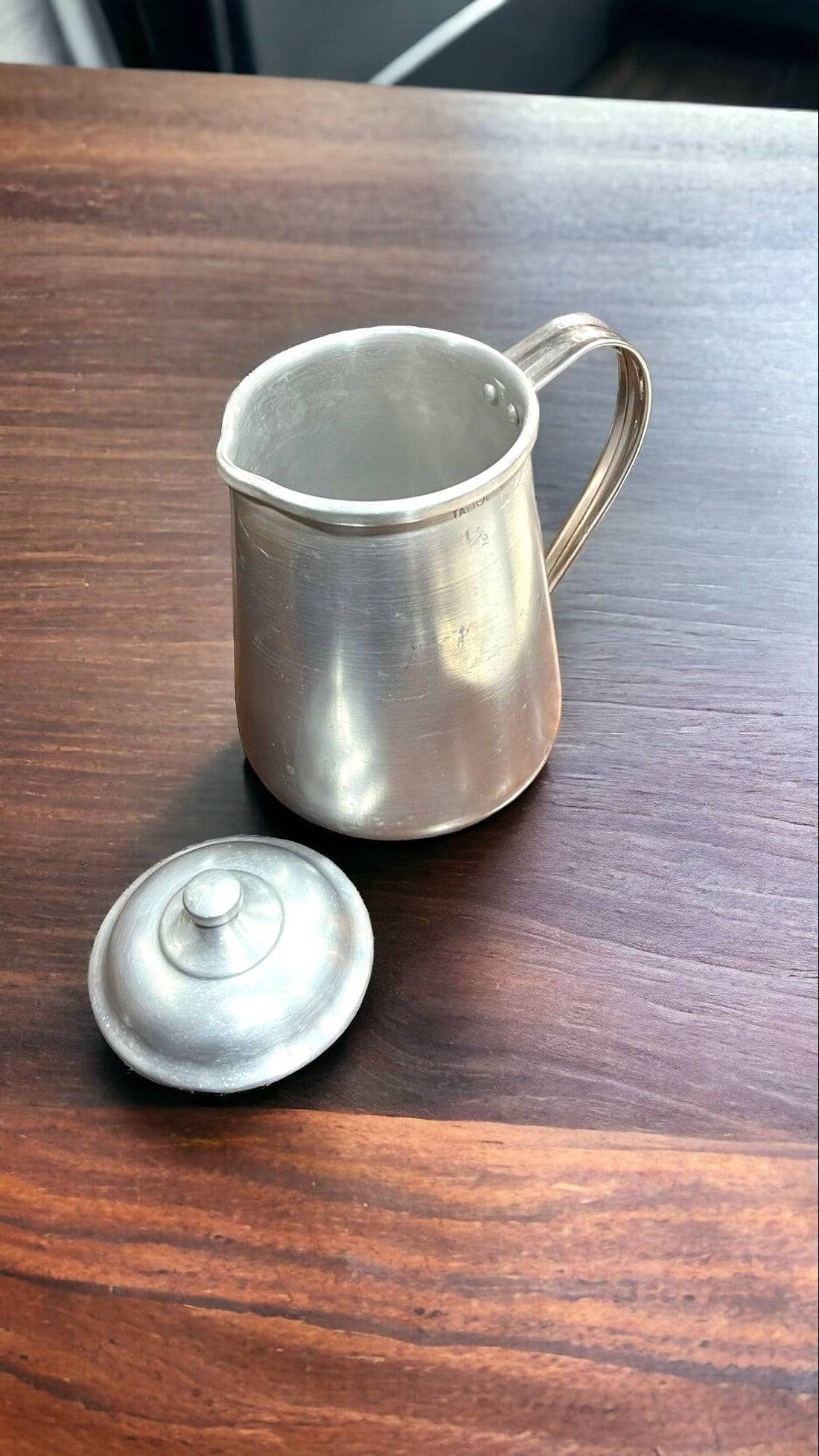 Jarra de aluminio vintage de 1/2 litro con tapadera para cocina sobre encimera moderna. Ideal para decoración retro en cocinas contemporáneas.