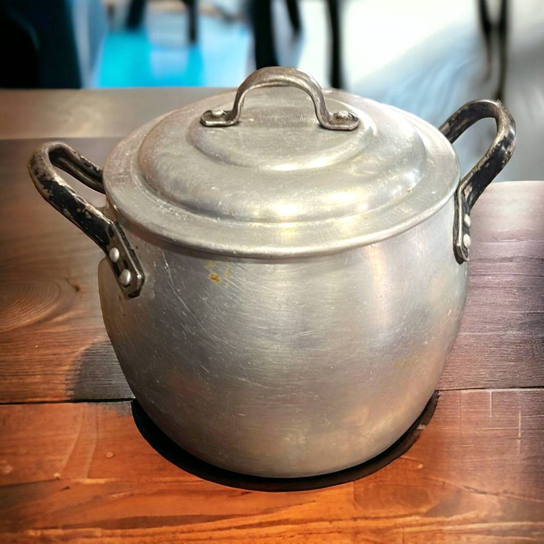 Olla de Aluminio Vintage con asas negras sobre mesa de madera, ideal para decoración rústica de cocina. Tradición y elegancia para tu hogar.