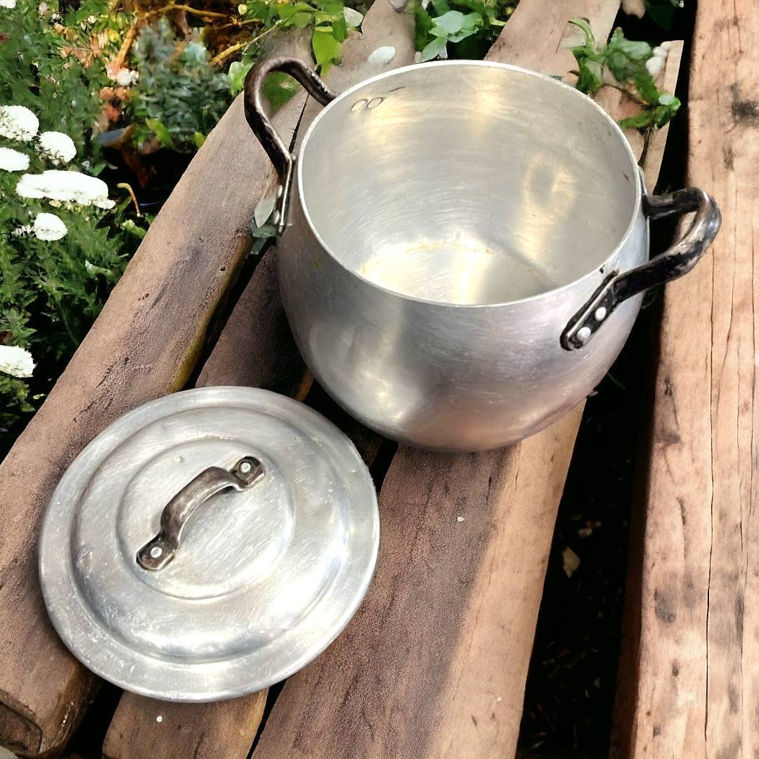 Olla de Aluminio Vintage con asas negras sobre mesa de madera, ideal para decoración rústica de cocina. Tradición y elegancia para tu hogar.