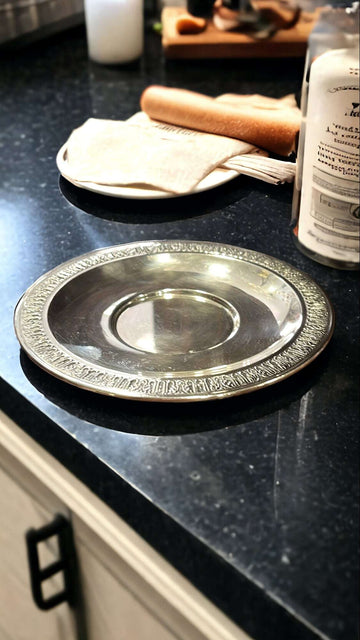 Plato multifuncional de metal plateado, versátil y elegante sobre encimera de cocina, ideal para decoración o servir alimentos con estilo.