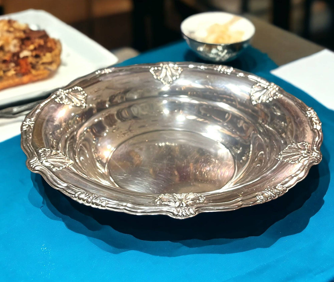 Plato redondo de metal plateado decorado con bordes en relieve, ideal para decoración de mesa elegante en hogar y eventos especiales.